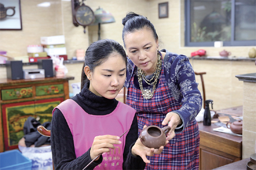 谈燕华（左）正在听其师傅顾勤指点壶艺