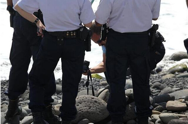法属留尼汪首府圣但尼附近的一处海滩上，警员正在现场对金属残片进行拍照